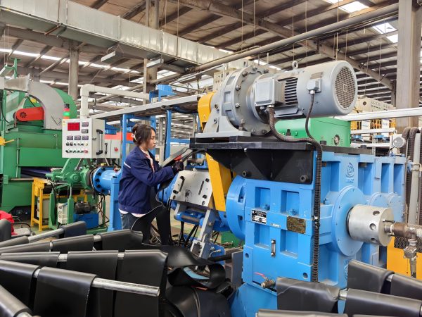 Technician performing maintenance on an extruder, checking alignment and components